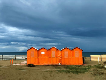 Beach hut by sea against sky