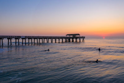 Silhouette pier over sea against sky during sunset