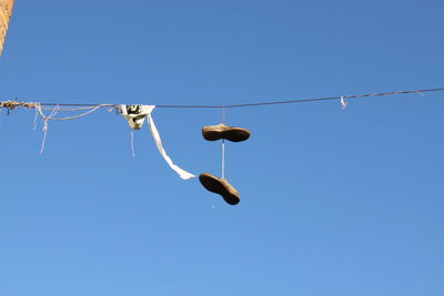 Low angle view of birds on cable against clear blue sky