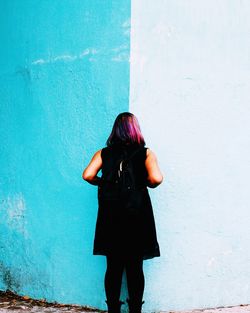 Rear view of woman standing against wall