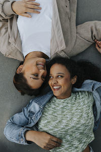 High angle view of smiling teenage girl lying together and looking at each other