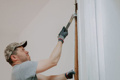 A young man is working with a crowbar in a doorway.