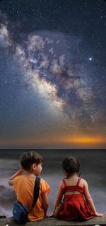 Friends on sea against sky at night