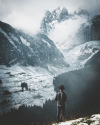 Rear view of man standing on snowcapped mountain