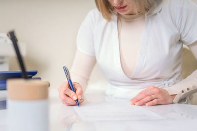 Midsection of woman holding paper while sitting on table