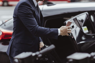 Midsection of businessman with smart phone sitting in car