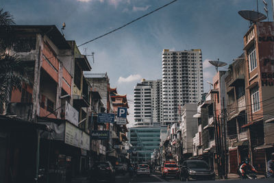 Traffic on city street by buildings against sky