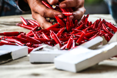 Close-up of hand holding red chili peppers on table