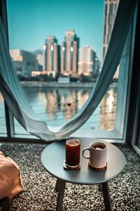 Low section of coffee cup on table against buildings