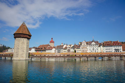 Buildings by river against sky