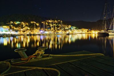 Illuminated moored boats in water at night