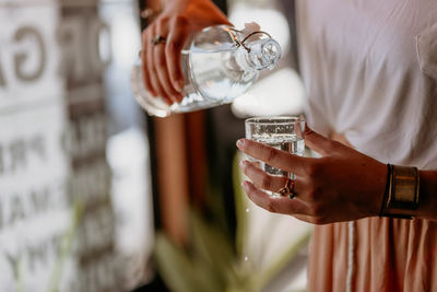 Close-up woman pouring water into a glass