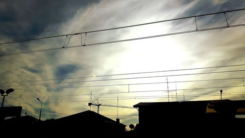 Low angle view of power lines against cloudy sky