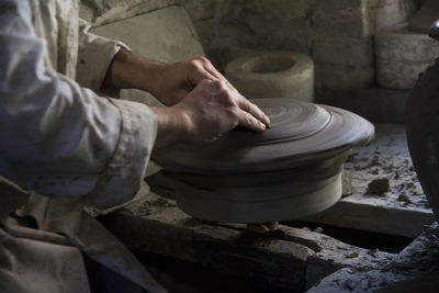 Midsection of man working on pottery wheel at workshop