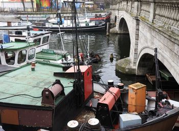 High angle view of fishing boats moored in river by arch bridge