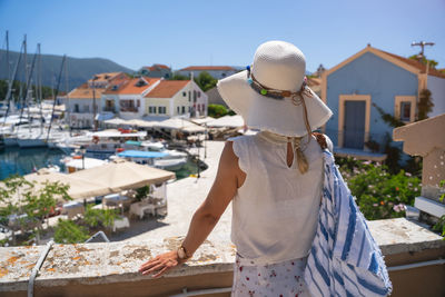 Rear view of man on boat against buildings on sunny day