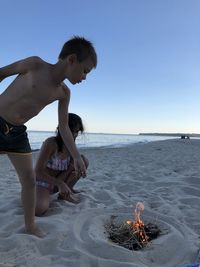 Full length of shirtless boy on beach against sky