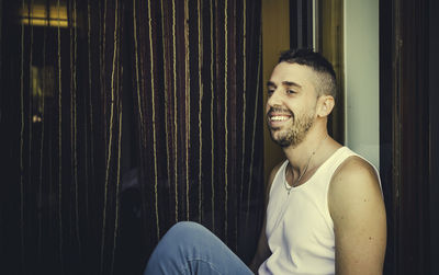 Portrait of young man sitting against window