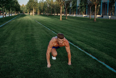 Full length of shirtless man in grass