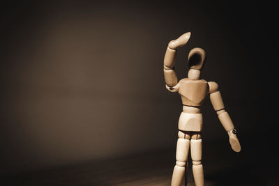 Close-up of wooden figurine on table against wall