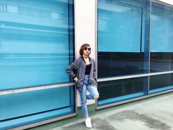 Full length portrait of woman leaning on buildings