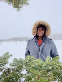 Portrait of woman standing in snow against clear sky during winter