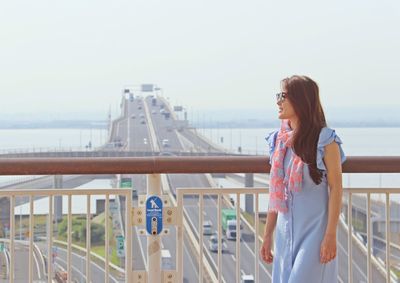 Woman standing by railing against sky