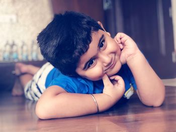 Portrait of cute boy lying on floor at home