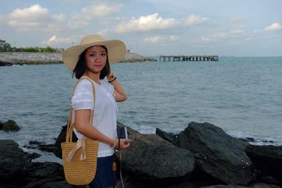 Portrait of woman standing by sea against sky