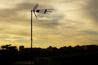 Low angle view of silhouette communications tower against sky