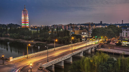 Illuminated city by buildings against sky at night