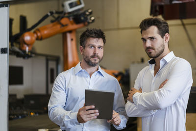 Young man holding camera while standing at home