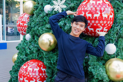 Portrait of man standing against christmas tree