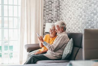 Young woman using mobile phone while sitting on sofa at home