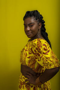 Young woman wearing colorful long clothes over yellow background. isolated yellow background.