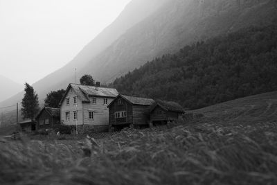 House on field by mountains against sky