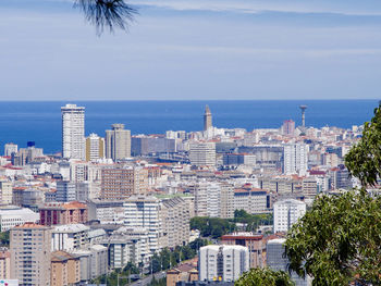 City buildings by sea against sky