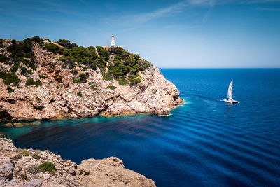 Scenic view of rocks by sea against sky