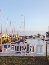 Sailboats moored at harbor against clear sky