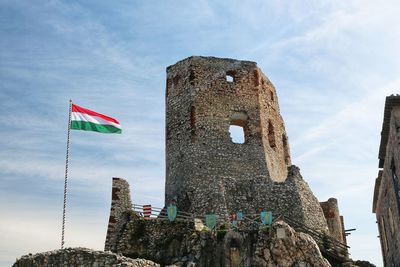 Low angle view of flag flags on old building against sky