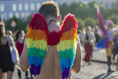 Rear view of shirtless man wearing rainbow costume wing on street during gay pride parade