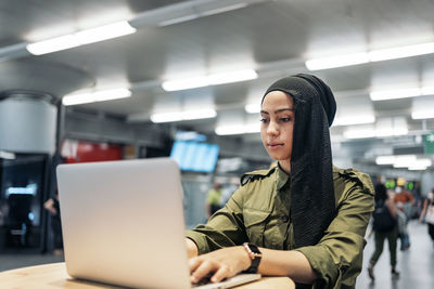 Modern muslim woman using her laptop in a train station coffe restaurant