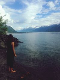 Rear view of woman standing in sea against sky