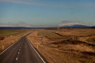 Road leading towards mountains against sky