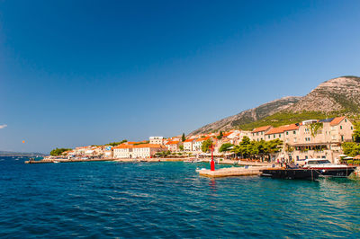 Scenic view of sea and buildings against clear blue sky