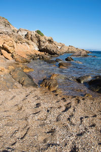 Rocks on beach against clear blue sky