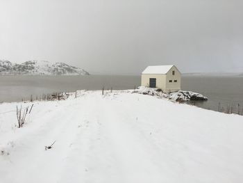Snow covered houses by building against sky