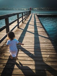 Toddler child running on a peer by a lake