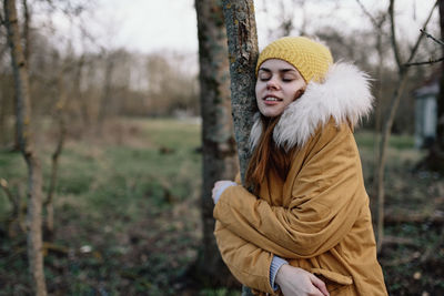 Portrait of young woman standing against trees