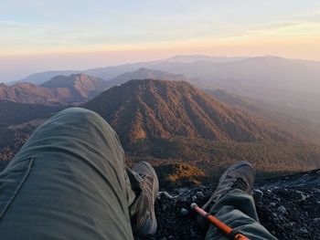 Low section of man on mountains against sky